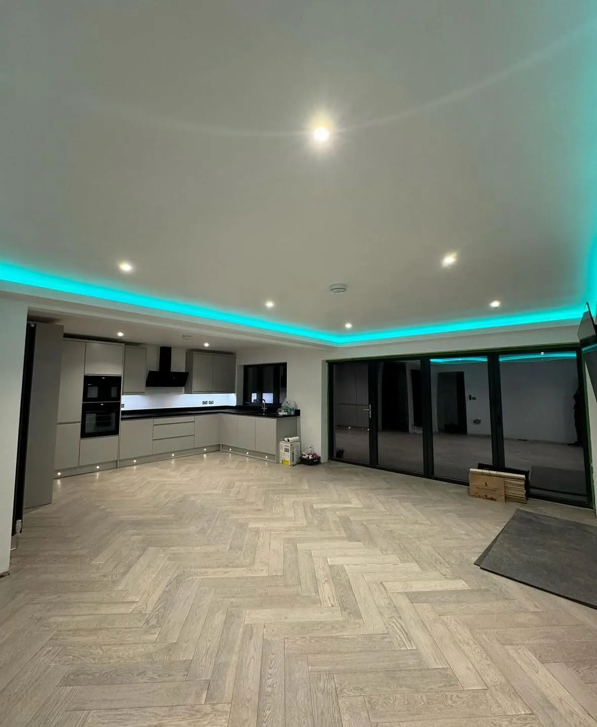 Open plan kitchen diner inside a completed extension, herringbone floor and bifold doors